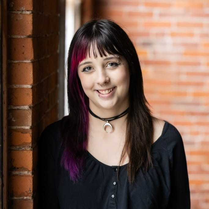 Portrait of Emry, a professional stylist at Revolutions Salon, showcasing their expertise and style.